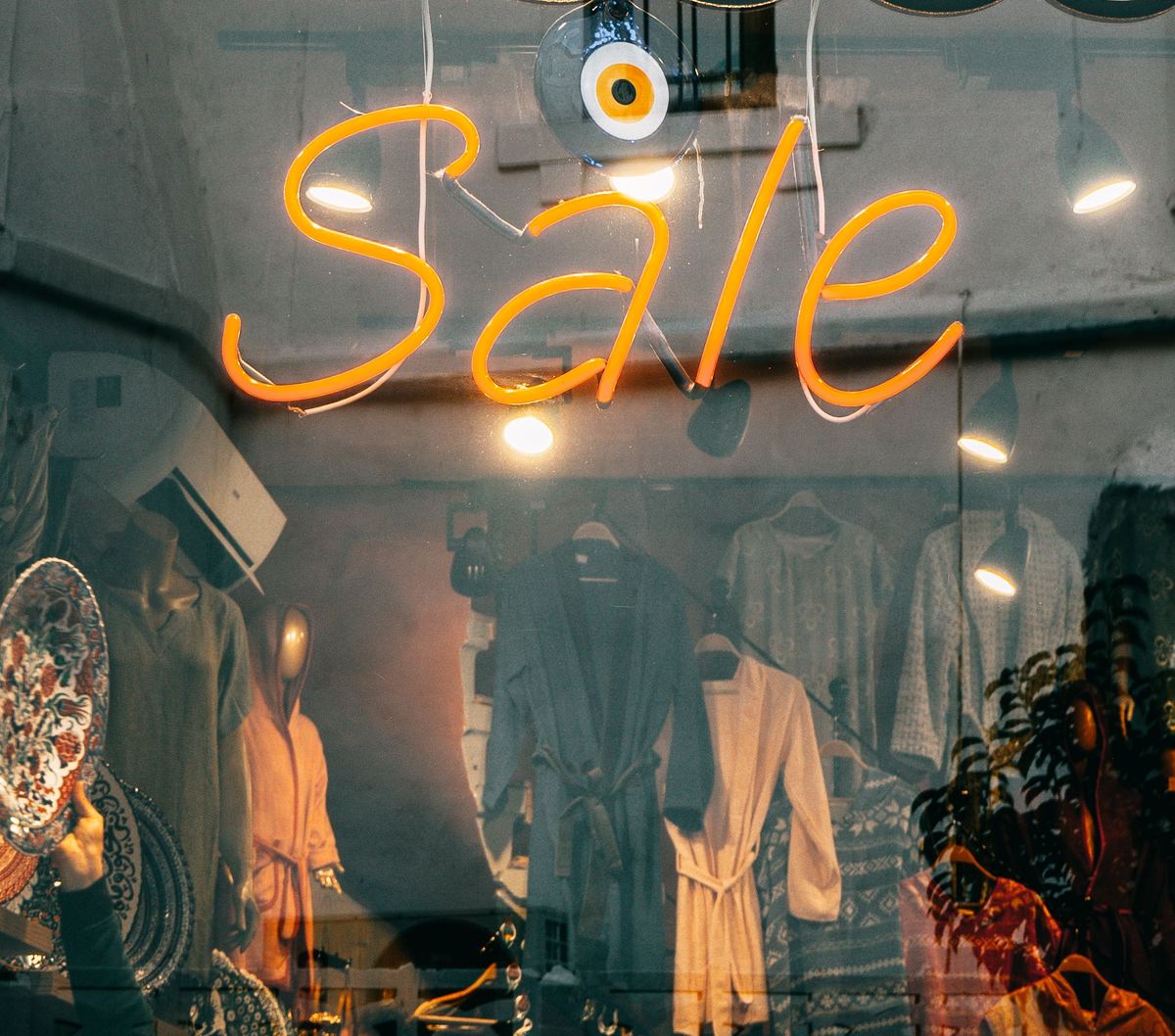 Sale neon sign glowing in a boutique storefront window at dusk